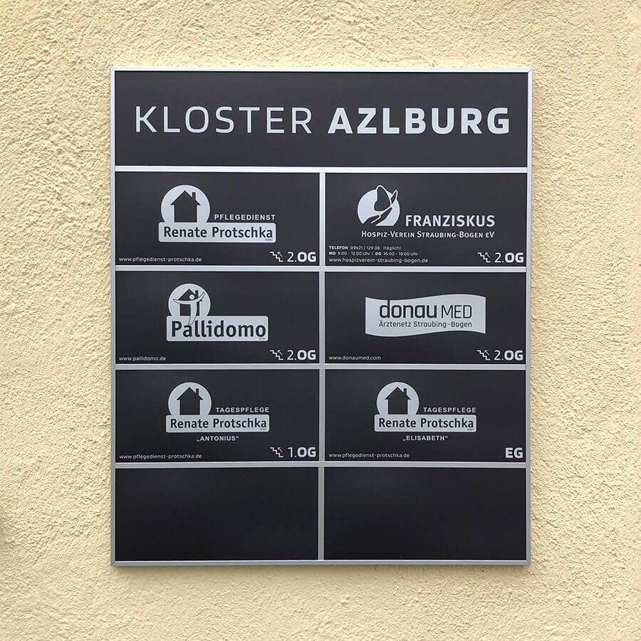 Wegweiser und Etagenbeschilderung an einer Fassade in Straubing